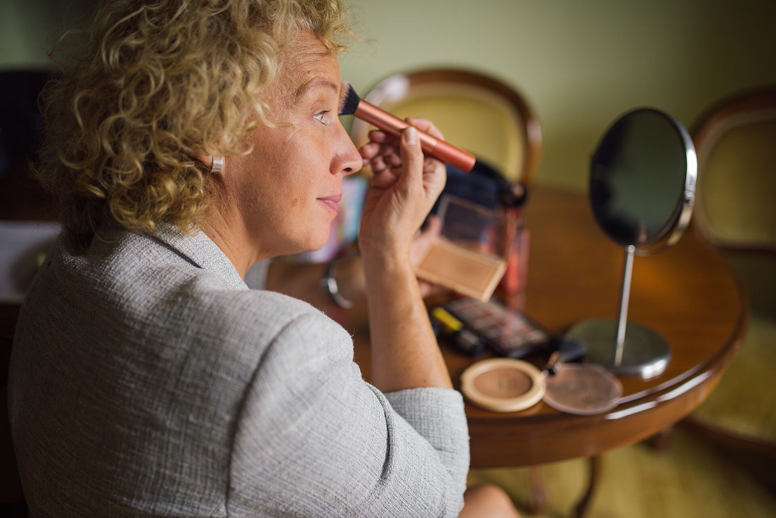 Une femme se maquille devant son miroir de coiffeuse